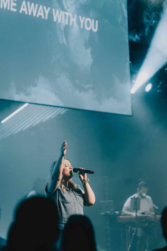 a woman singing into a microphone in front of a crowd